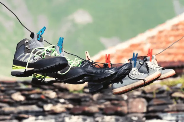 Image showing shoes hanging from a line. Drying is a good option for how to stop shoes from squeaking.