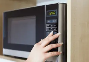 Woman pressing on the buttons of a microwave