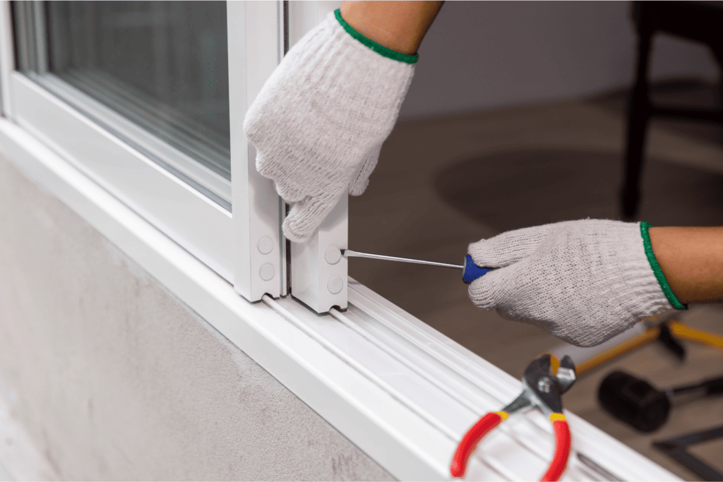 Someone adjusting sliding glass door on its rail