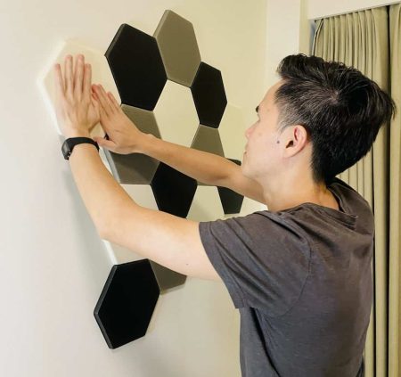 Ludovic Chung-Sao installing acoustic panels on a white wall